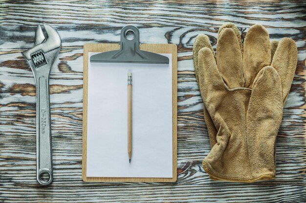 Protective gloves adjustable spanner pencil clipboard on wooden board