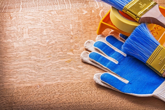 Protective gloves duct tape paint tray and brushes on wooden board construction concept