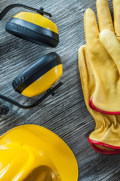 Protective gloves hard hat earmuffs on wooden board