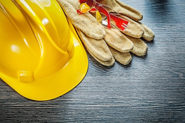 Protective gloves hard hat goggles on wooden board