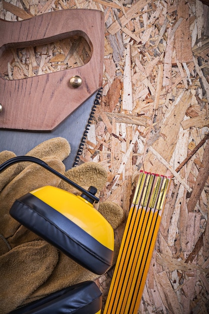 Protective leather gloves wooden meter handsaw earmuffs on OSB