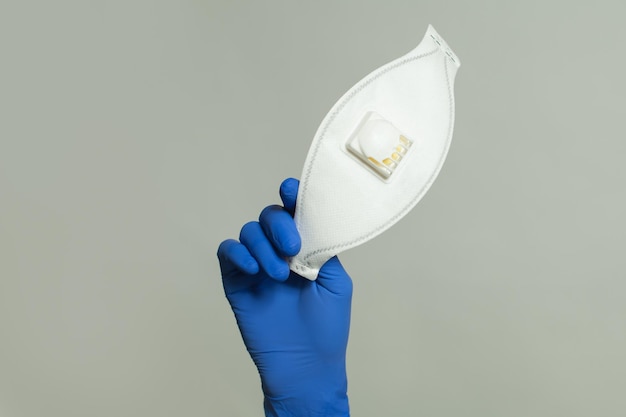 Protective mask in doctor hand on gray background safety and virus protection concept