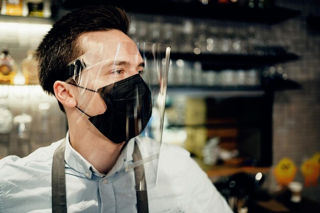 Photo protective mask on the face from the virus pandemic flu works in his small business restaurant cafe