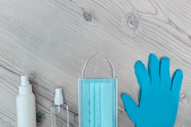 Photo protective mask, gloves and antiseptics on a wooden background. photo with a copy-space