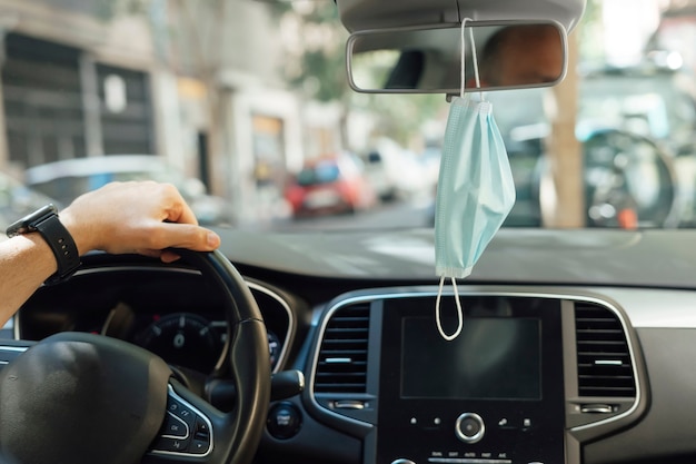 Protective mask hanging from the rear view mirror of a car