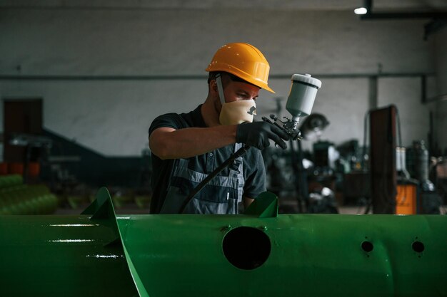 In protective mask painting details man in uniform is in workstation developing details of agriculture technique