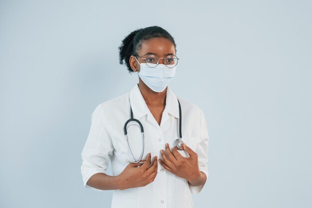 In protective mask young african american woman is against\
white background