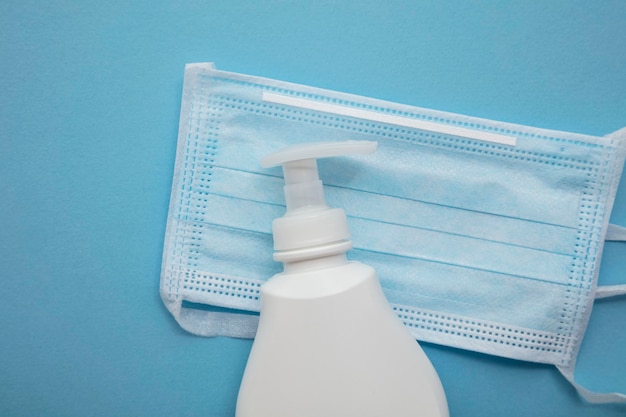 Protective medical mask and anti bacterial hand soap on a blue background