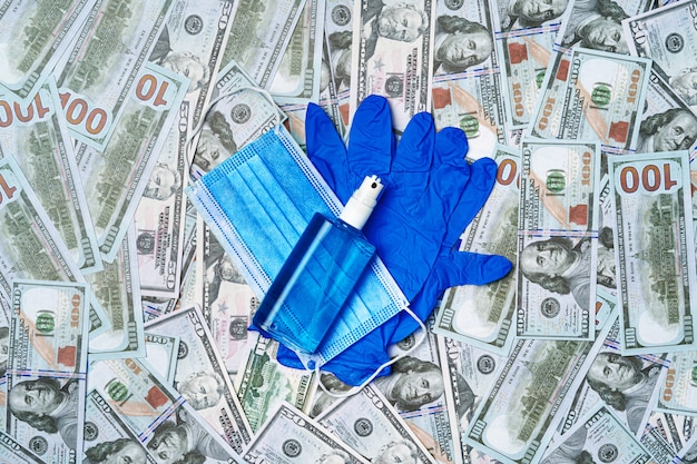 Protective medical mask, gloves and sanitizer on a ofus dollar banknotes