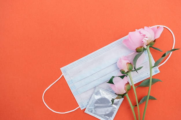 Protective medical mask, peony and a condom.Concept of love relationship in new normal reality.