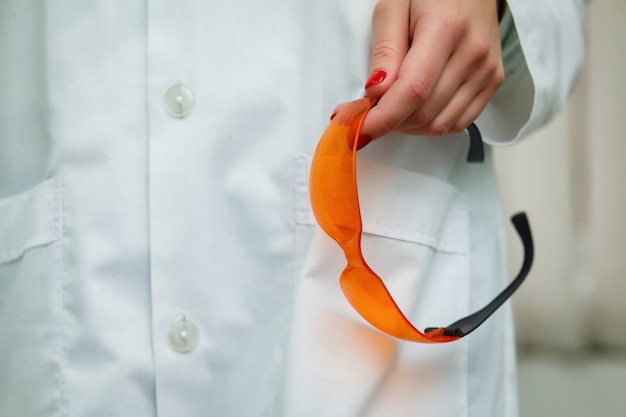 Protective orange glasses in the hand of the dentist. 