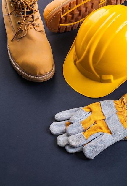 Protective working wear construction helmet work gloves working boots on black background