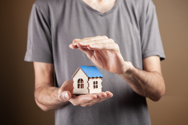 Protects the house with his hands on a brown background