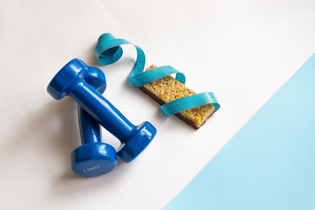 Protein bar without sugar for a slim figure tape measure and dumbbells on a white background