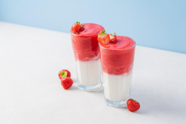 Protein rich smoothies with yogurt and frozen strawberries in glass on light background