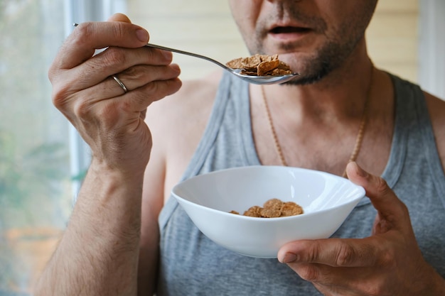 Protein and vitamins Man at home room eating natural vegetarian granola buckwheat flakes Closeup of an unrecognizable man