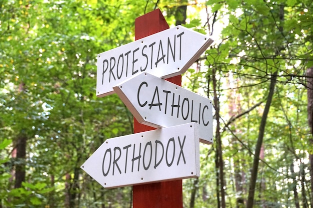 Protestant catholic orthodox wooden signpost with three arrows forest in background