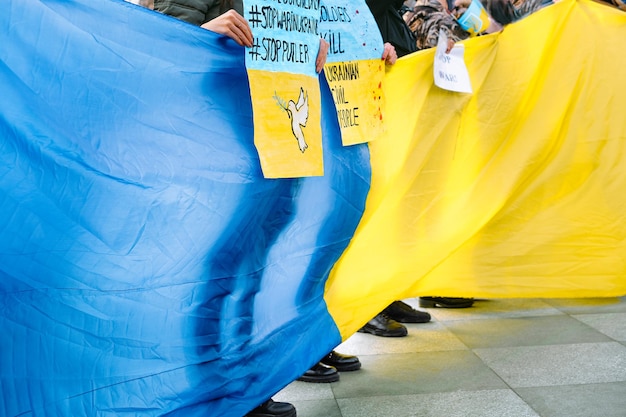 Foto manifestanti a una manifestazione anti-guerra con striscioni e bandiera ucraina