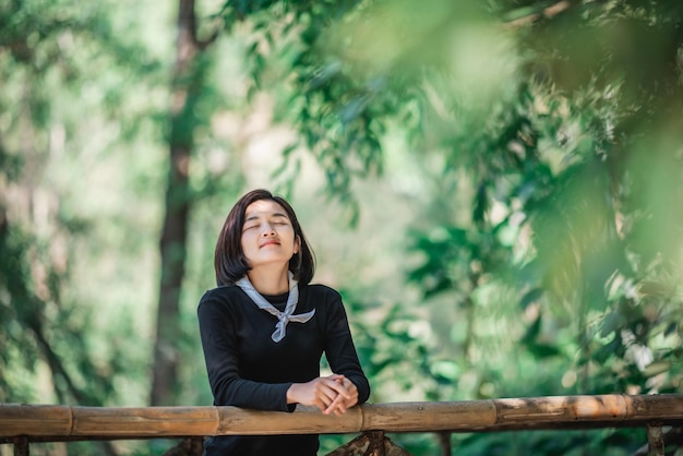 Protrait young woman standing on bamboo bridge smile and looking beautiful nature while camping in forest with happy copy space