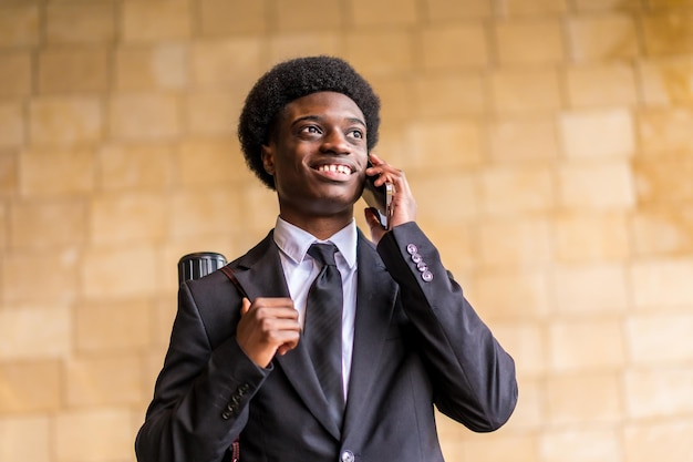 Photo proud african architect talking to the mobile and smiling outdoors