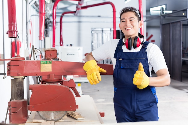 Proud Asian carpenter showing thumbs up