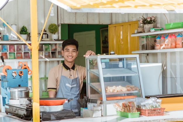 写真 屋台の食べ物を売るトラックコンテナで作られた彼の店で誇り高き若いアジア人中小企業の所有者