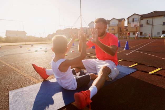 Proud young father motivating his little son to train with him.