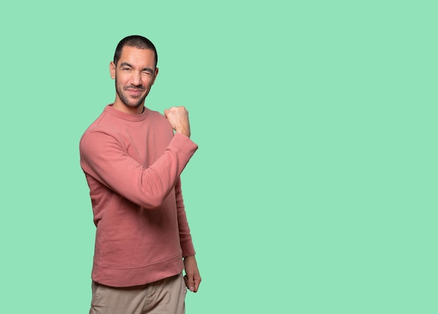 Proud young man doing a gesture of strength with his arm