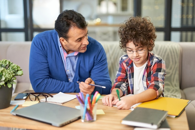 Fornisci a tuo figlio il miglior padre latino di mezza età premuroso che controlla i compiti aiutandolo