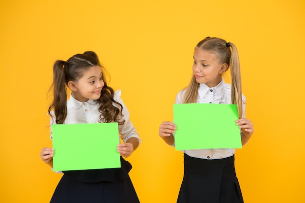 情報を提供する 黄色の背景に空の緑色の紙を持って情報を得る小さな子供 情報の通知を表示する小さな女の子 未来はインテリジェントな広告コピースペース