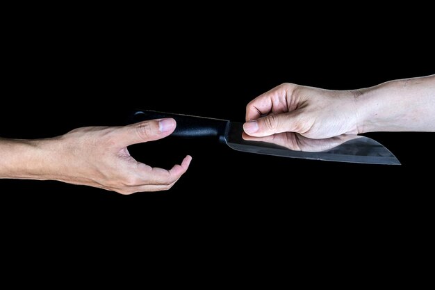 Photo providing the knife from hand to hand in a black background