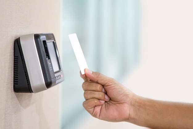 Считыватель бесконтактных карт разблокирует дверь. Ручной охранник использует удостоверение личности на системе контроля доступа со сканированием отпечатков пальцев для проверки личности, чтобы открыть дверь, или для обеспечения безопасности, или для проверки посещаемости.
