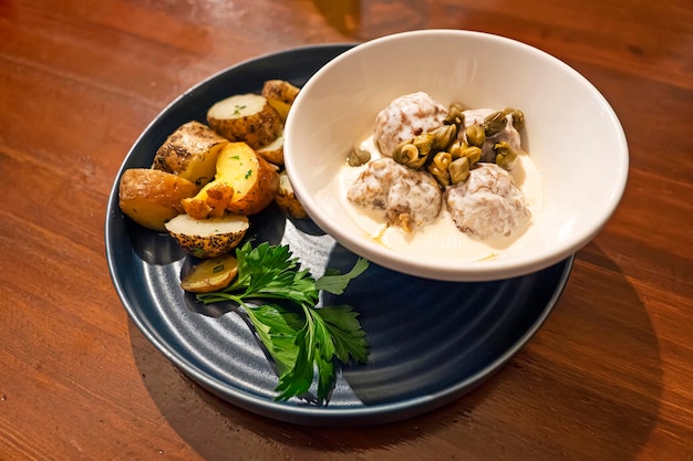 Pruisische specialiteit van Königsberger Klopse - gekookte gehaktballen in een witte saus met ansjovis, jonge aardappelen, kappertjes en rode biet.