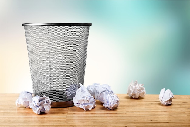 Foto prullenbak met vellen papier op houten tafel