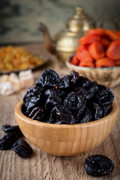 Prunes in a bamboo bowl on an old wooden. Healthy dried fruit