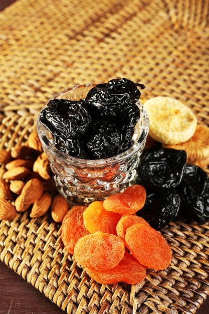 Prunes and other dried fruits on wicker mat closeup