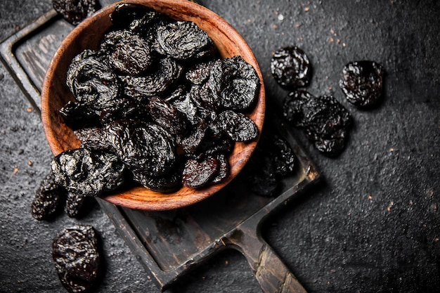 Prunes in a plate on a cutting board