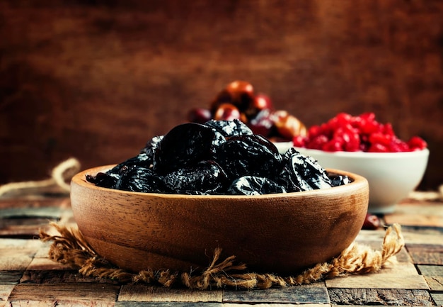 Prunes in wooden bowl rustic style selective focus