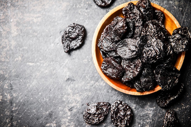 Prunes in a wooden plate on the table