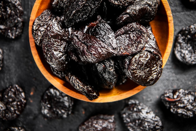 Prunes in a wooden plate on the table