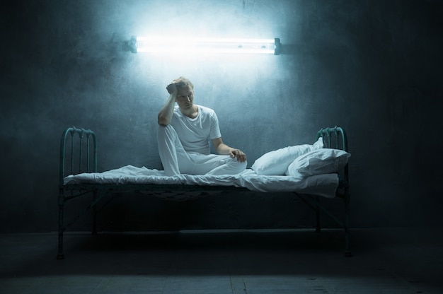 Premium Photo  Blindfolded crazy man sitting in bed, dark room..  psychedelic male person having problems every night, depression and stress,  sadness, psychiatry hospital