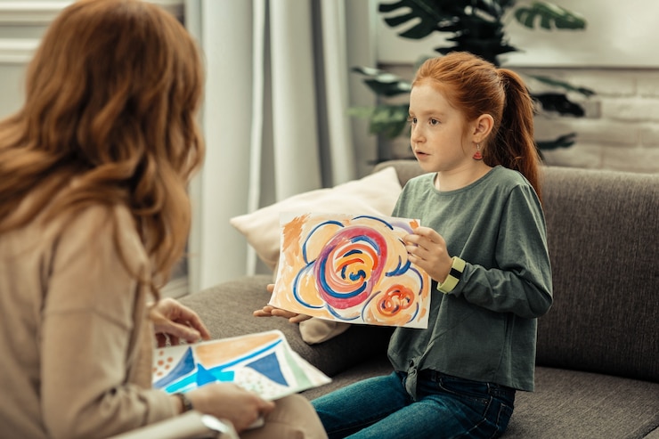 Photo psychological test. cute pleasant girl holding a colorful painting while speaking about it