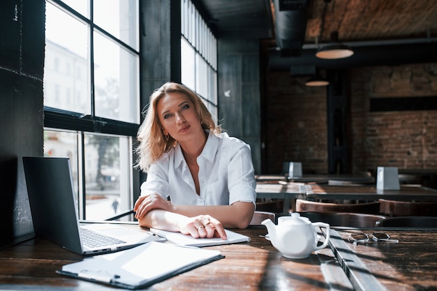 Psychologist listens to the patient. Businesswoman with curly blonde hair indoors in a cafe at daytime.