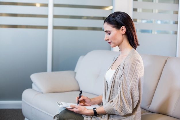 Psychologist sitting on the couch and taking notes