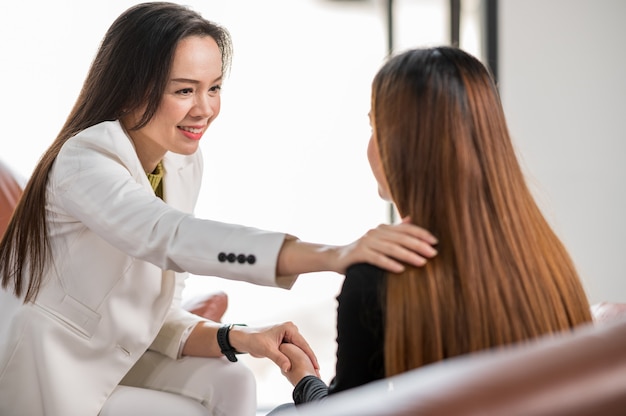 Psychologist touch the shoulder and provide assistance understanding problems of a woman patient