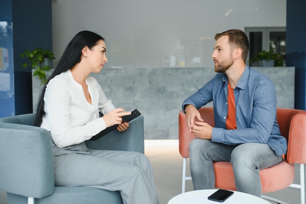 Psychology mental therapy and people concept woman psychologist talking to sad young man patient at psychotherapy session