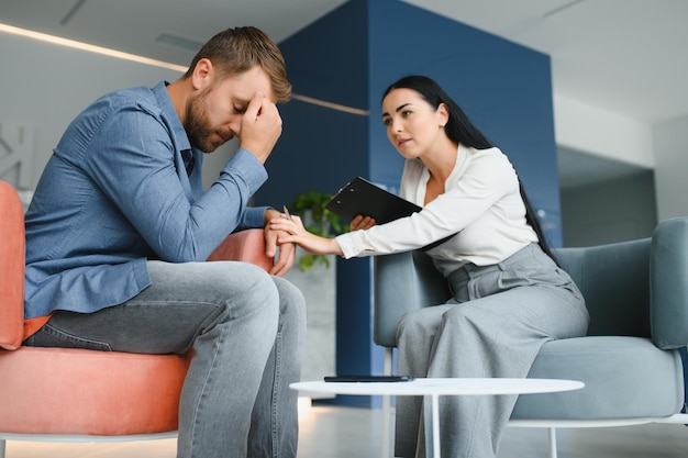 Psychology mental therapy and people concept woman psychologist talking to sad young man patient at psychotherapy session