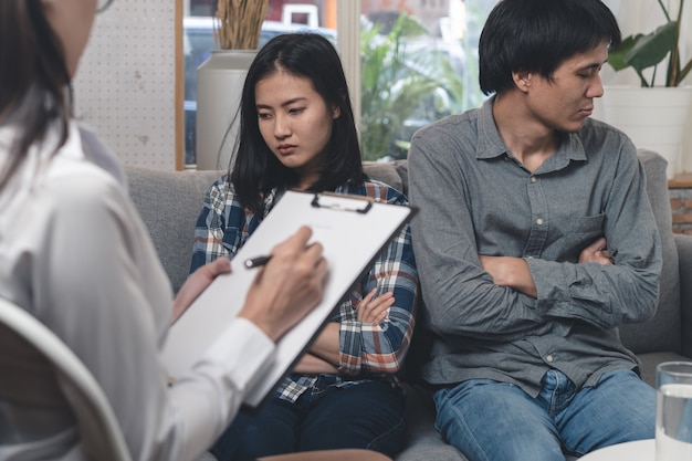 Psycholoog die met Aziatisch echtpaar bij kliniek spreekt.