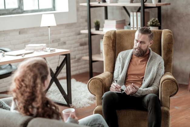 Psycholoog luisteren. Donkerharige, bebaarde psycholoog die luistert naar een tienermeisje met een depressie