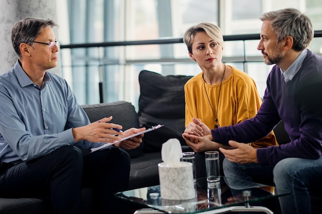 psychotherapist having a meeting with mid adult couple at his office